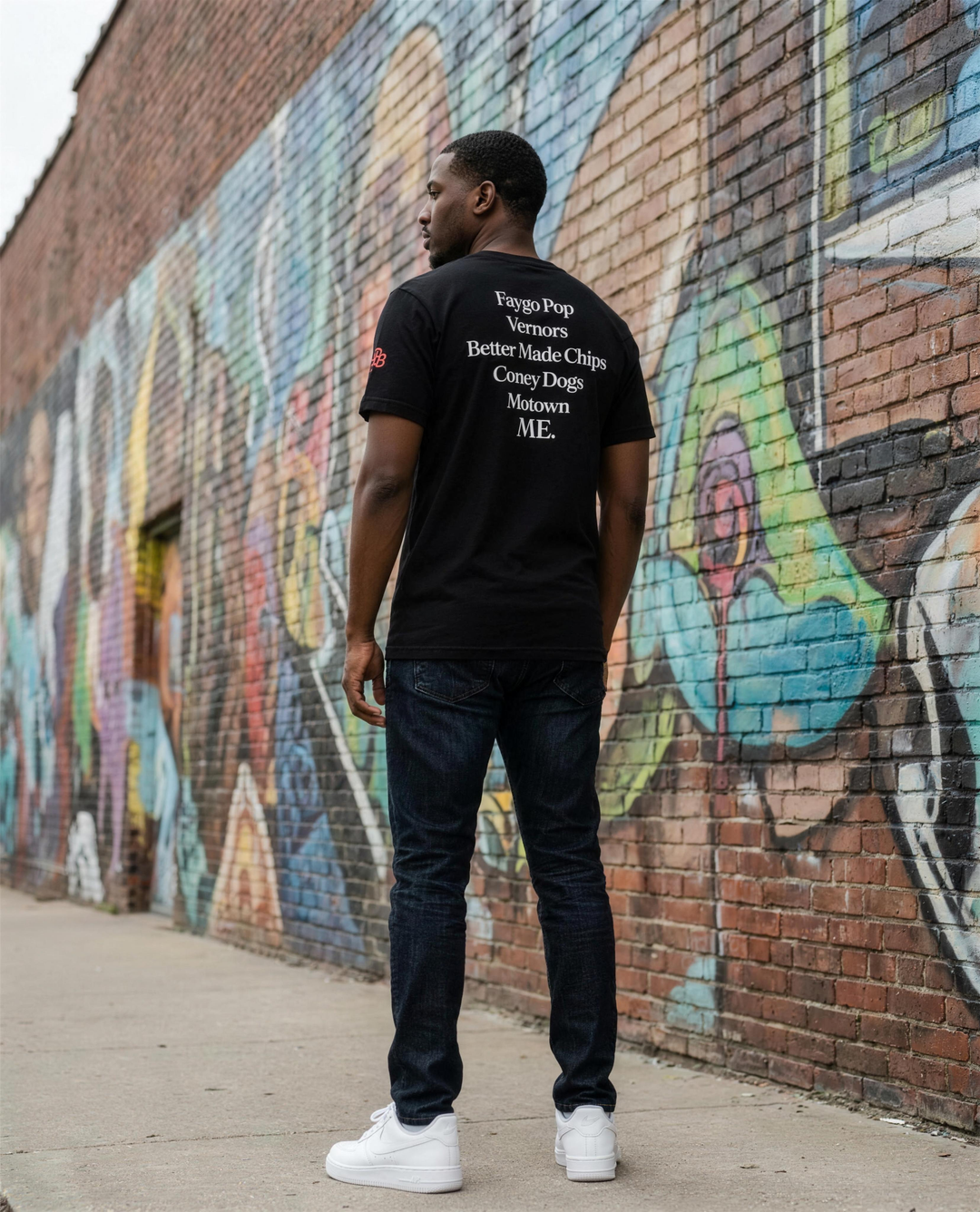 Back print of the Retro Black Made In Detroit t-shirt worn by a Black man at an Eastern Market mural in Detroit